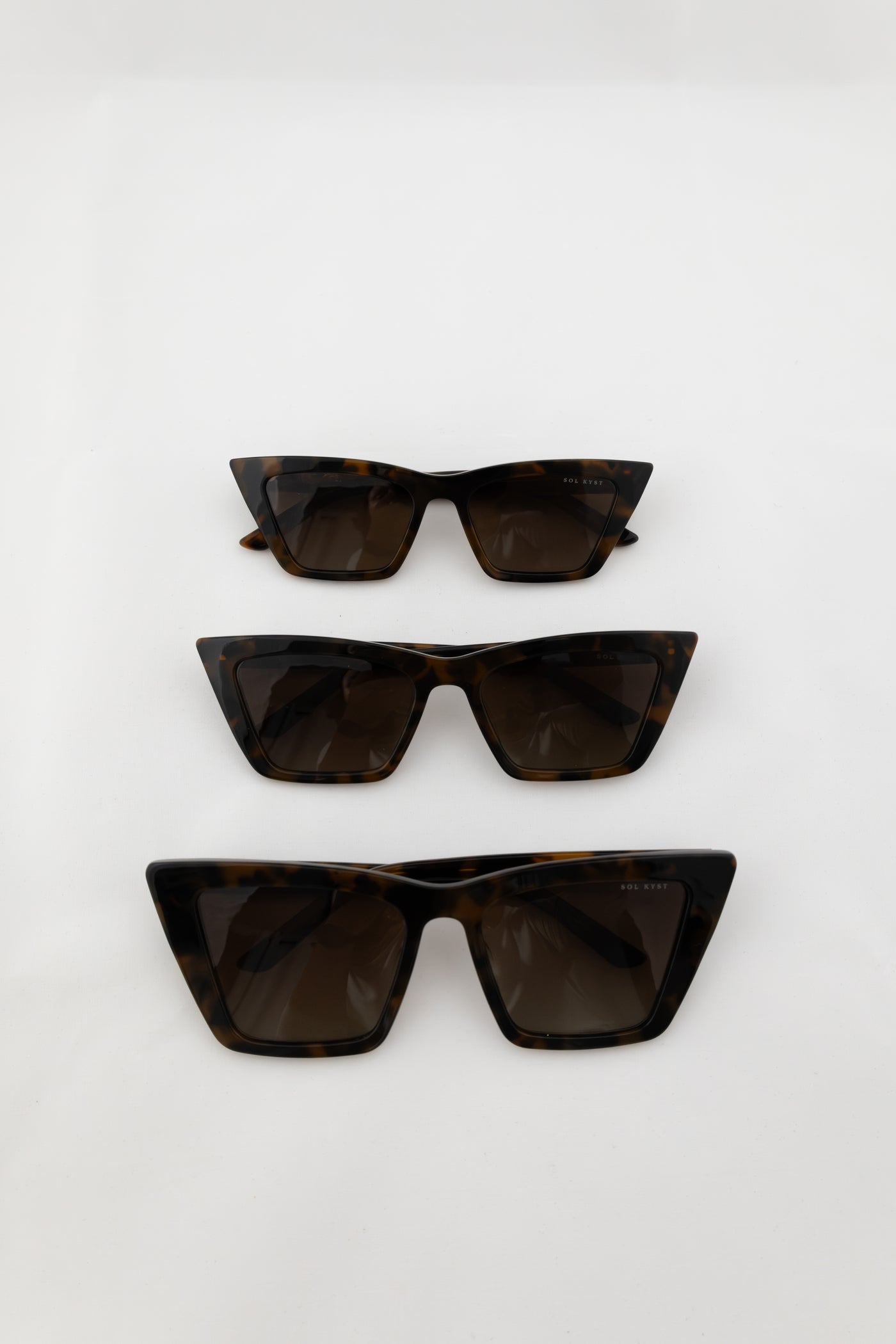 Three pairs of tortoise trapezoid sunglasses with dark lenses displayed in a vertical arrangement on a white background.