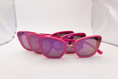 Multiple pairs of cat eye sunglasses showcasing bold pink frames, purple-tinted lenses, and gold Sol Kyst accents.