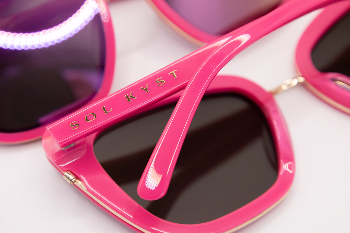 Sol Kyst cat eye sunglasses arm in pink with gold branding, showcasing luxury eyewear details.